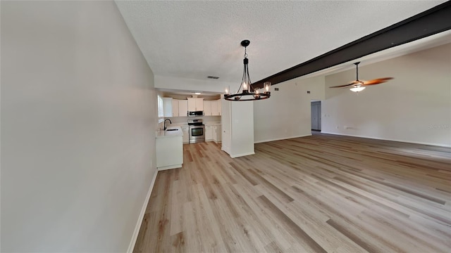 interior space with sink, ceiling fan with notable chandelier, a textured ceiling, and light hardwood / wood-style floors