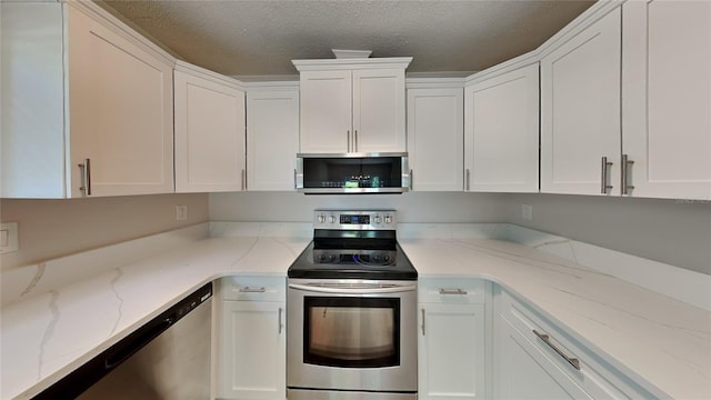 kitchen with appliances with stainless steel finishes, light stone counters, a textured ceiling, and white cabinets