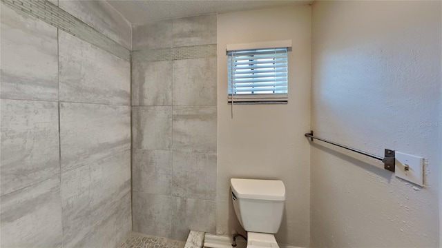 bathroom featuring tiled shower and toilet