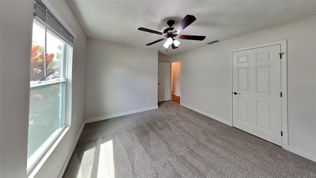 unfurnished bedroom with a textured ceiling, light colored carpet, and ceiling fan