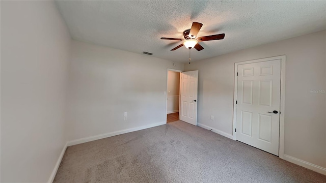 unfurnished bedroom with light carpet, a textured ceiling, and ceiling fan