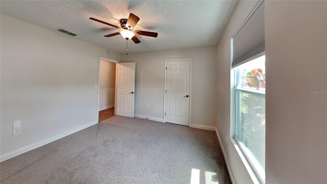 unfurnished bedroom featuring ceiling fan, a textured ceiling, and light colored carpet