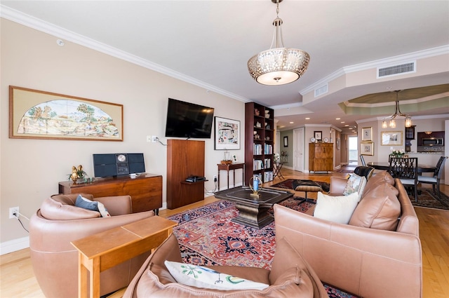 living room with crown molding, a notable chandelier, and light wood-type flooring