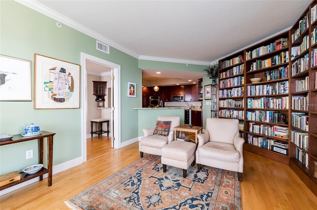 living area featuring light hardwood / wood-style flooring and ornamental molding