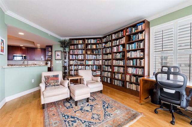 sitting room with crown molding and light hardwood / wood-style flooring