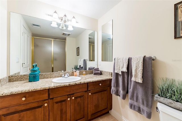 bathroom featuring toilet, walk in shower, vanity, and tile patterned floors