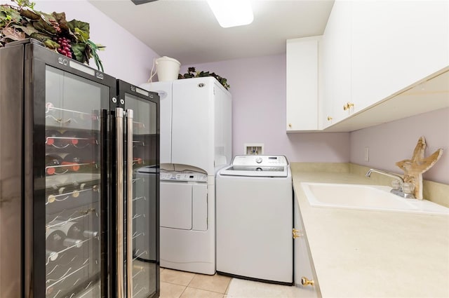 washroom featuring washer and dryer, cabinets, sink, and light tile patterned floors