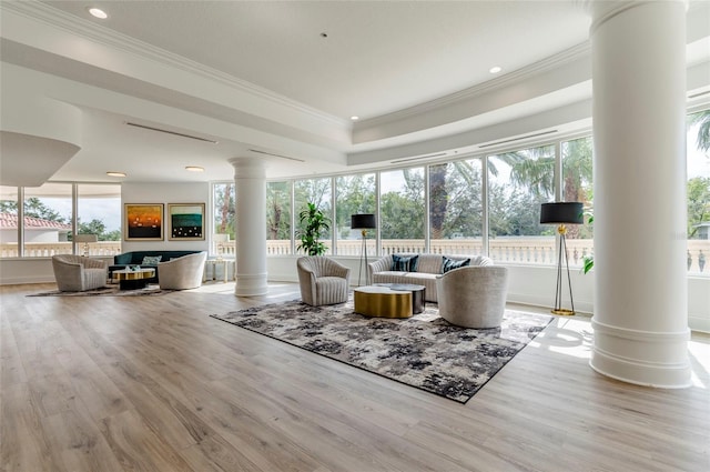 interior space featuring ornate columns, ornamental molding, and light wood-type flooring