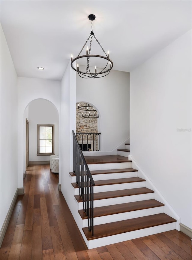 stairs featuring wood-type flooring and a notable chandelier