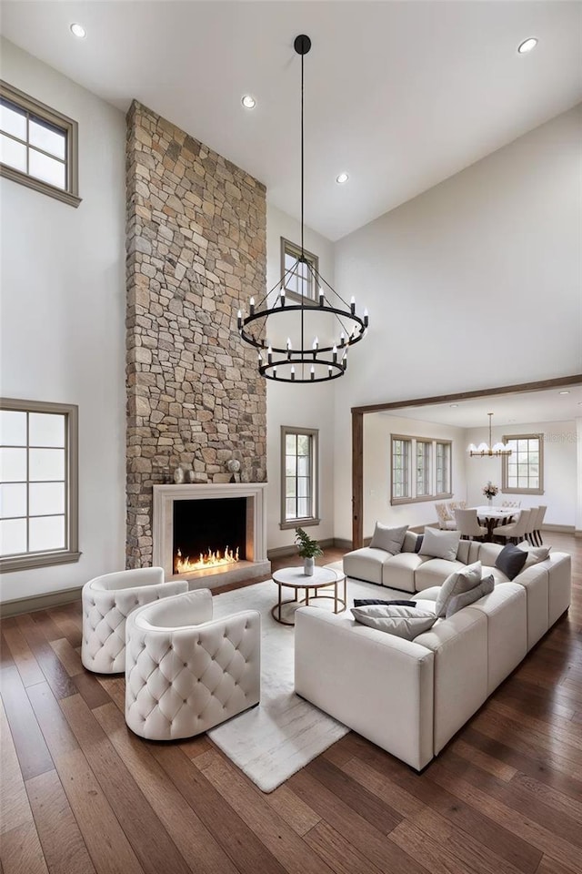 living room featuring dark hardwood / wood-style flooring, a notable chandelier, a high ceiling, and a fireplace