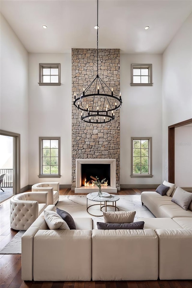 living room featuring a fireplace, a towering ceiling, wood-type flooring, and a healthy amount of sunlight