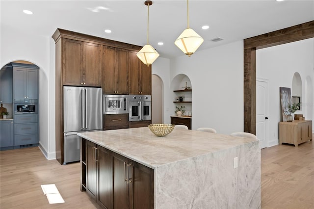 4633 W Lowell Ave, Tampa, FL 33629 - kitchen with stainless steel appliances, arched walkways, light wood finished floors, recessed lighting, and a kitchen island