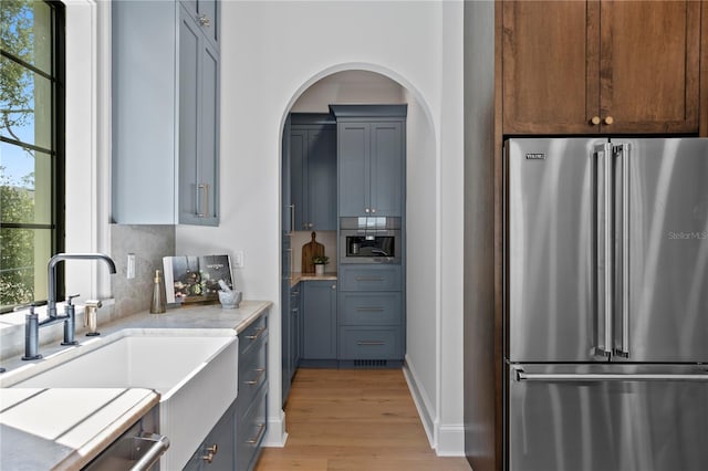 4633 W Lowell Ave, Tampa, FL 33629 - kitchen featuring high end fridge, light wood-style flooring, tasteful backsplash, a sink, and light countertops