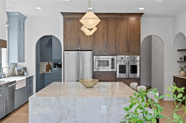 4633 W Lowell Ave, Tampa, FL 33629 - kitchen featuring appliances with stainless steel finishes, arched walkways, a sink, light stone counters, and recessed lighting