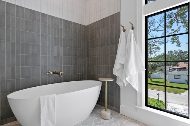4633 W Lowell Ave, Tampa, FL 33629 - bathroom featuring tile walls, a freestanding bath, plenty of natural light, and tile patterned flooring