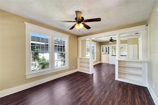 empty room featuring dark wood-style floors, a textured ceiling, a ceiling fan, and baseboards