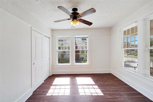 unfurnished room featuring dark wood-style floors, a healthy amount of sunlight, and a textured ceiling