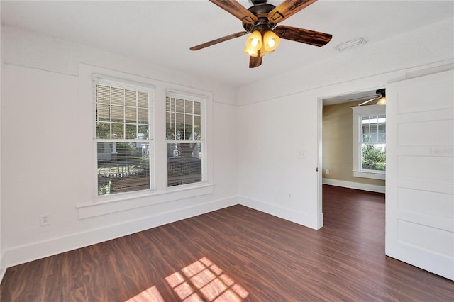 unfurnished room with dark wood-type flooring, visible vents, baseboards, and a ceiling fan