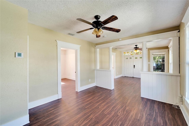 empty room featuring visible vents, baseboards, a ceiling fan, dark wood-style floors, and a textured ceiling