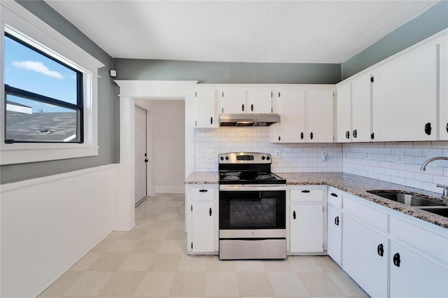 kitchen with light stone counters, under cabinet range hood, a sink, white cabinetry, and electric stove