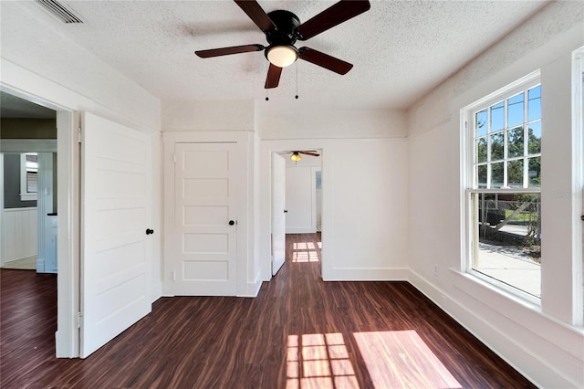 unfurnished room with dark wood-style floors, visible vents, a textured ceiling, and baseboards