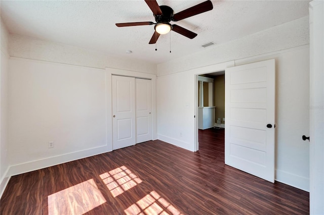 unfurnished bedroom featuring a closet, dark wood finished floors, visible vents, and baseboards