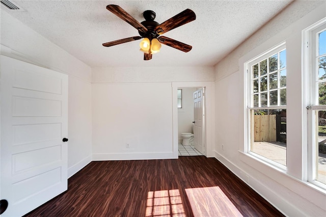 spare room featuring dark wood-style floors, visible vents, a textured ceiling, and baseboards