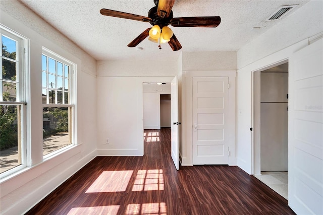 empty room featuring dark wood-style floors, baseboards, visible vents, and a textured ceiling