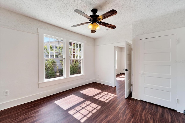 unfurnished bedroom with a textured ceiling, ceiling fan, dark wood finished floors, and baseboards