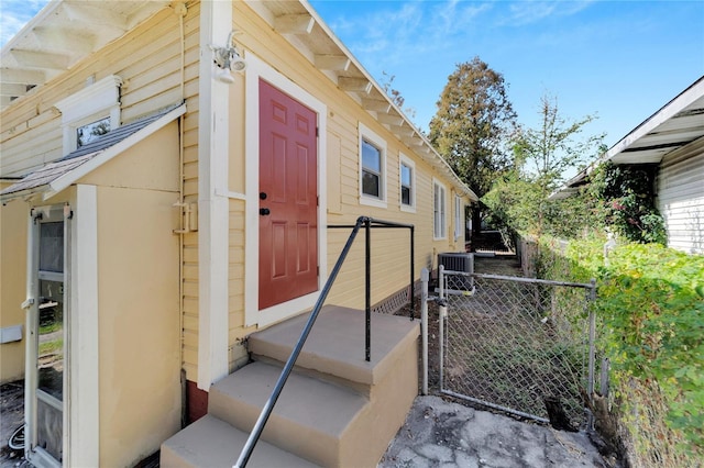 doorway to property featuring a gate, fence, central AC, and stucco siding