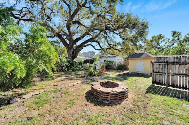 view of yard with a storage shed, an outdoor fire pit, an outdoor structure, and fence