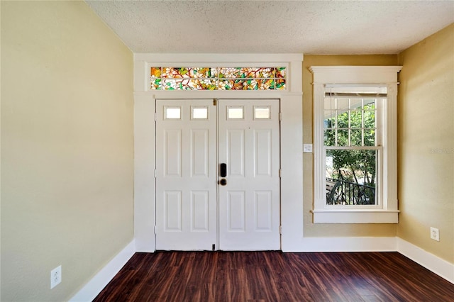 entrance foyer with dark wood-style flooring, a textured ceiling, and baseboards