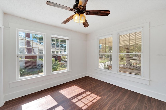 spare room with a ceiling fan, dark wood-style flooring, a textured ceiling, and baseboards