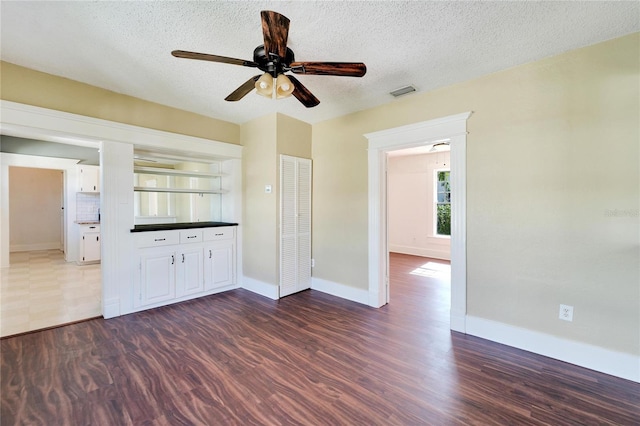 unfurnished room featuring dark wood-style floors, a textured ceiling, and baseboards