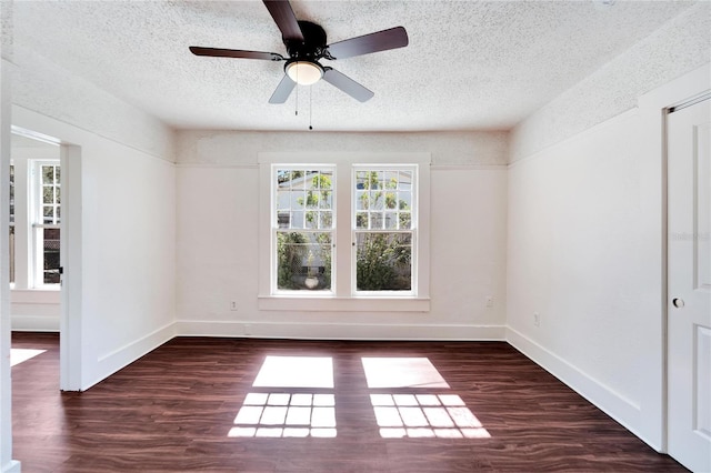 empty room featuring a textured ceiling, dark wood-type flooring, and baseboards