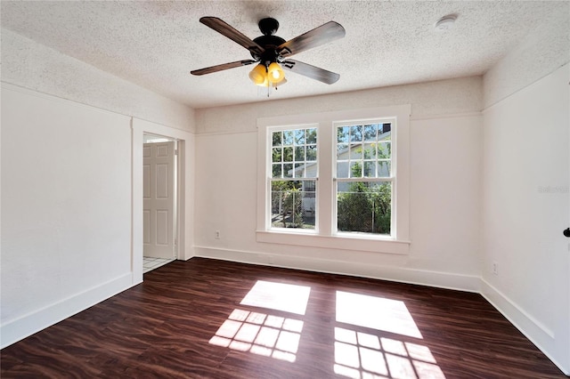 spare room with a textured ceiling, ceiling fan, dark wood finished floors, and baseboards