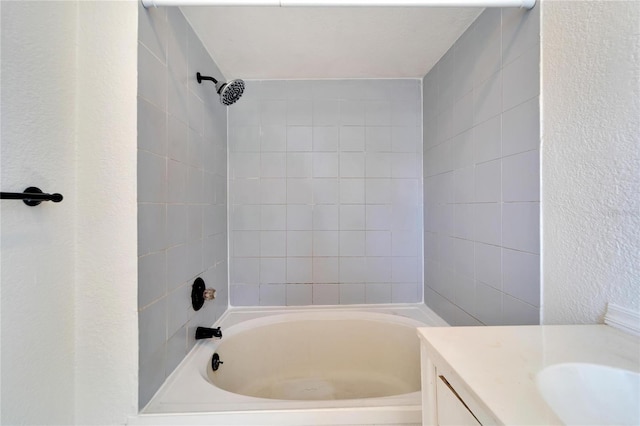 full bath featuring tub / shower combination, a textured wall, and vanity