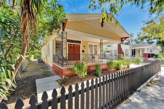 view of front of house featuring a fenced front yard, central AC unit, and a porch