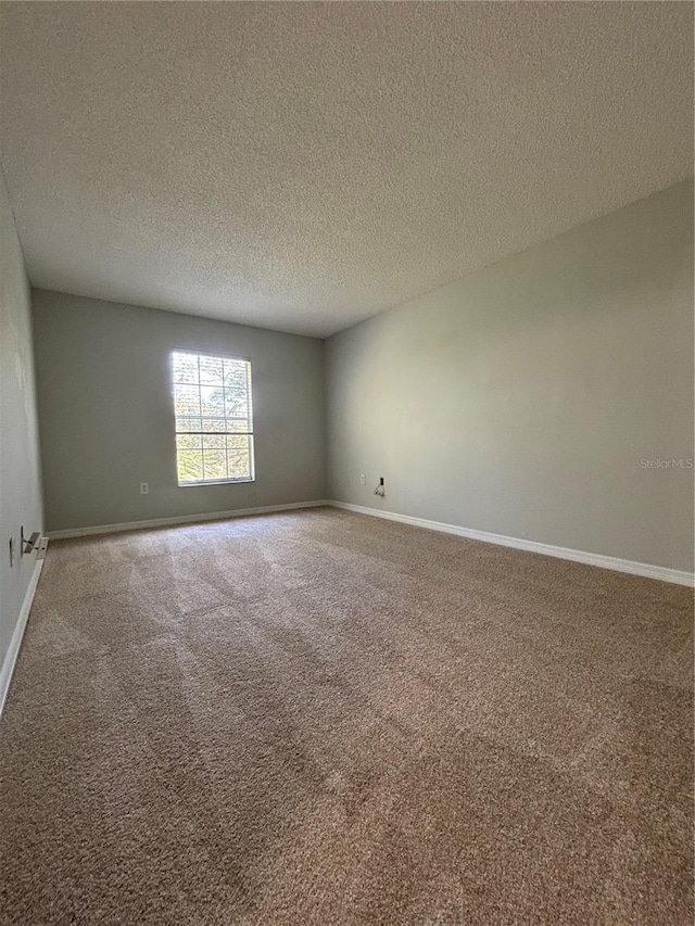 spare room with a textured ceiling and carpet flooring