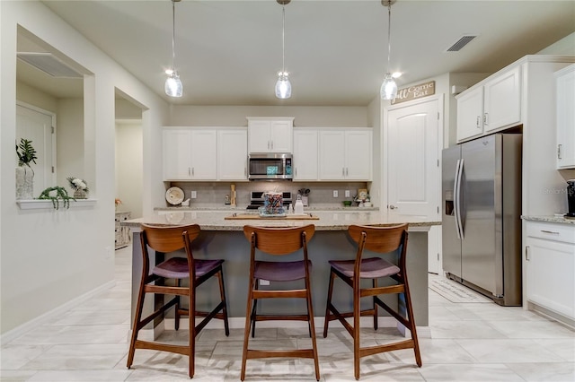 kitchen featuring light stone counters, stainless steel appliances, pendant lighting, and an island with sink