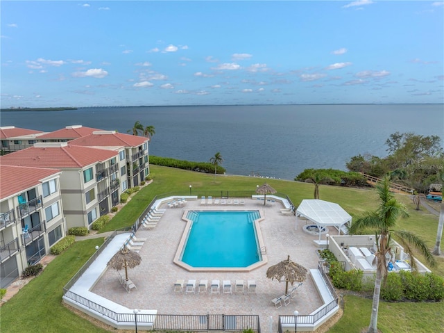 view of pool featuring a yard, a patio, and a water view