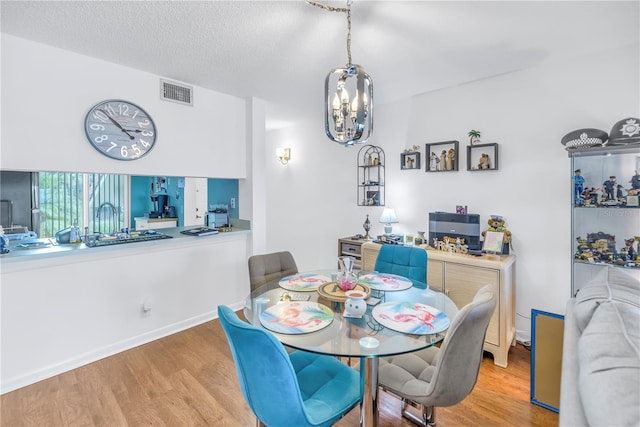 dining space featuring a chandelier, a textured ceiling, and light hardwood / wood-style flooring