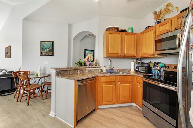 kitchen featuring stainless steel appliances, a textured ceiling, light stone countertops, sink, and kitchen peninsula