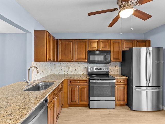 kitchen featuring sink, light hardwood / wood-style flooring, decorative backsplash, light stone countertops, and stainless steel appliances