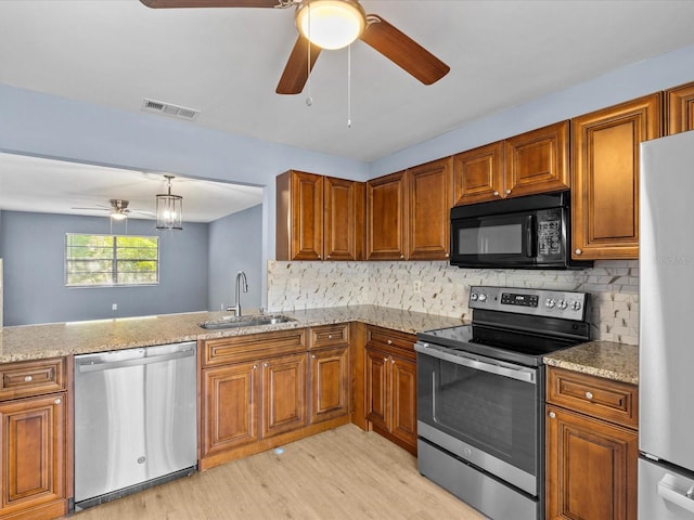 kitchen featuring backsplash, sink, light wood-type flooring, appliances with stainless steel finishes, and kitchen peninsula