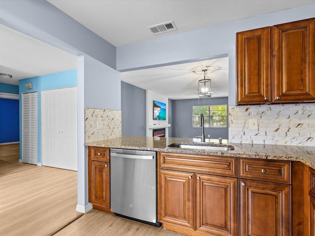 kitchen featuring light stone countertops, stainless steel dishwasher, sink, a notable chandelier, and light hardwood / wood-style floors