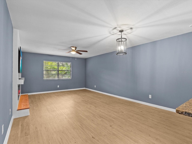 unfurnished room with light hardwood / wood-style floors and ceiling fan with notable chandelier