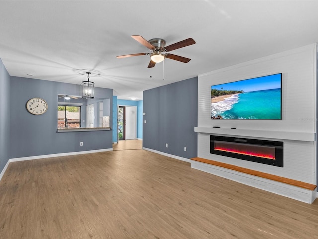 unfurnished living room featuring ceiling fan with notable chandelier and light wood-type flooring