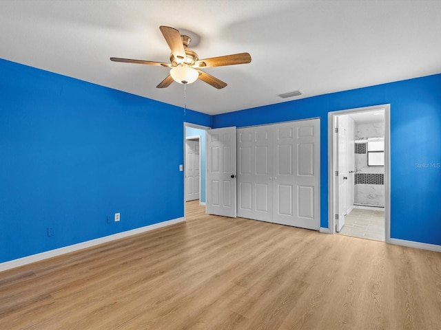 unfurnished bedroom with ensuite bathroom, ceiling fan, light wood-type flooring, and a closet