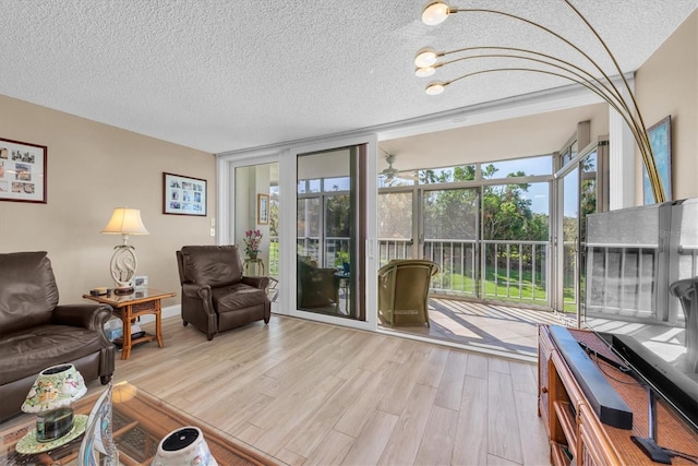 living room featuring light wood-type flooring, a textured ceiling, and a wall of windows